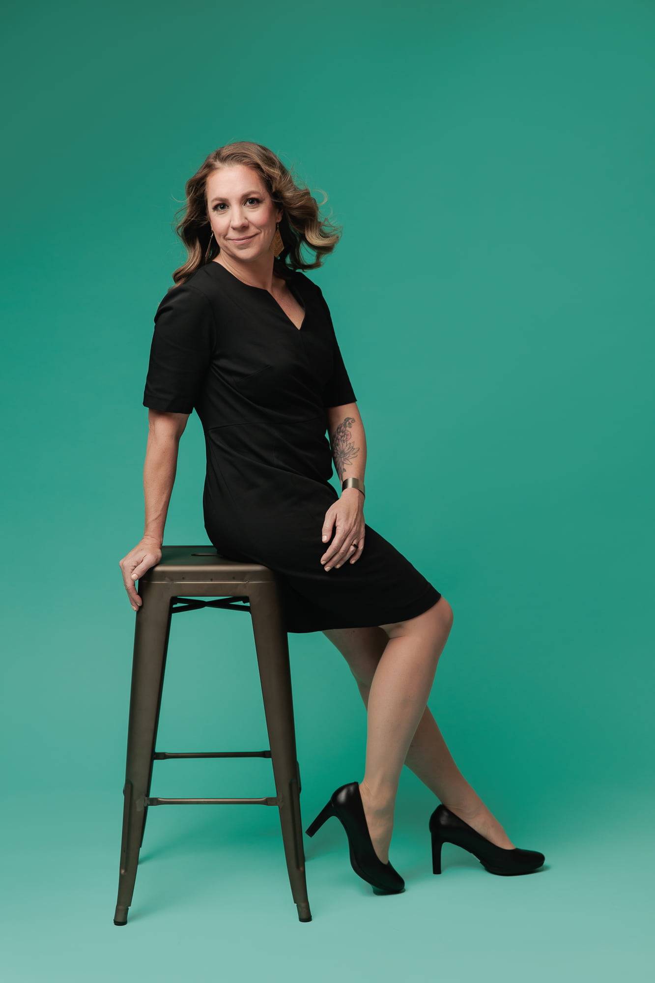 calgary-glam-photography-by-amanda-dams-portraits-woman-sitting-on-stool-mint-background-black-dress